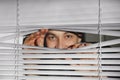 Curious man looking through Venetian window Royalty Free Stock Photo