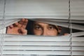 Curious man looking through Venetian window Royalty Free Stock Photo