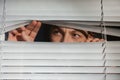 Curious man looking through Venetian window Royalty Free Stock Photo