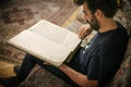 Curious man reading old book in his library at home Royalty Free Stock Photo