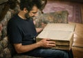 Curious man reading old book in his library at home Royalty Free Stock Photo