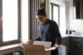 Curious mixed race woman receive shipment box with ordered goods