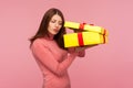 Curious nosy woman with brown hair in pink sweater unboxing big yellow present and secretly peeping inside Royalty Free Stock Photo