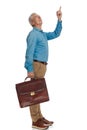 Curious old man with grey hair holding suitcase, looking up and pointing finger Royalty Free Stock Photo