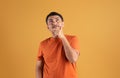 Curious pensive brazilian man touching chin looking up at copy space for advertisement, posing on orange background