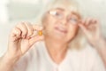 Curious retired woman viewing pill at home