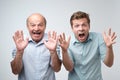 Curious shocked men, standing in casual shirts, isolated on pure background with wonderment.