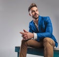 Curious smart casual man sitting on blue wood bench and praying