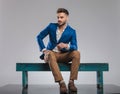 Curious smart casual man sitting on bench looks to side