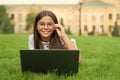 curious smart child in glasses explores the laptop computer working on her school homework, childhood education Royalty Free Stock Photo