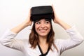 Curious, smiling woman in a white shirt, taking off or putting on Oculus Rift VR Virtual reality 3D headset