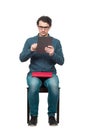 Curious student man seated on a chair using a PC tablet while holds a red book on his knees. Choose modern computer education