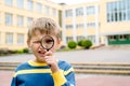 Curious surprised boy. One schoolboy with magnifier near his eye in the school yard. young researcher, training and