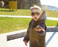 Curious surprised white boy in black sunglasses holding a stone and opening mouth.