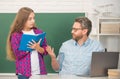 curious teen girl and teacher man in high school with workbook and pc at blackboard, communication