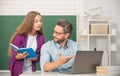 curious teen girl and teacher man in high school with workbook and pc at blackboard, parenthood