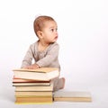 Curious toddler boy in cream clothes playing with books Royalty Free Stock Photo