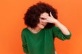 Curious woman with Afro hairstyle wearing green casual style sweater spying, hiding and peeping Royalty Free Stock Photo