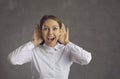 Curious woman listening with hands at both ears and looking at camera with surprised face expression Royalty Free Stock Photo