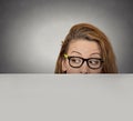 Curious woman peeking over edge of blank empty paper billboard