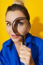 Curious woman is peering through magnifying glass with great interest, examining something closely