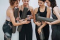 Curious women socialising at yoga club, looking at phone screen