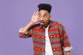 Curious young african american guy in casual colorful shirt posing isolated on violet wall background studio. People Royalty Free Stock Photo