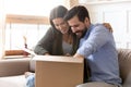 Curious young couple unpacking cardboard parcel package together
