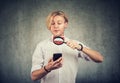 Curious young man using mobile phone with magnifying glass Royalty Free Stock Photo