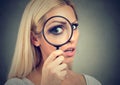 Curious young woman looking through a magnifying glass