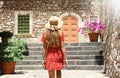 Curious young woman with red dress and hat walking in street in Taormina, Italy. Rear view of happy cheerful girl visiting Sicily Royalty Free Stock Photo