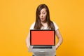 Curious young woman in white casual clothes holding laptop pc computer with blank empty screen isolated on bright yellow Royalty Free Stock Photo