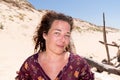 Curl brunette middle aged woman in sand beach dunes coast enjoying sunshine