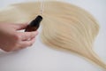 Curl female hair, balm or hair mask isolated on white background . Close-up oil bottle and recovery hair. Concept