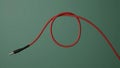 Curled Red Audio Jack Cable Ready for Connection Against Green Background Royalty Free Stock Photo