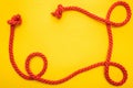 Curled and red rope with twisted knots isolated on orange. Royalty Free Stock Photo