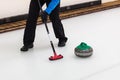 Curling - player with broom sweeping the ice before stone