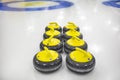 The curling stone or rock is made of granite with yellow handles lie