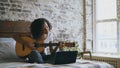 Curly african american teenager girl concentraing learning to play guitar using laptop computer sitting on bed at home Royalty Free Stock Photo