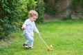 Curly baby girl playing in garden with wooden toy