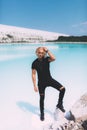 Curly blond man posing at the clear beach. Dressed all black. Awesome background, clear water and sky. Trendy, tropical and Royalty Free Stock Photo