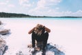 Curly blond man posing at the clear beach. Dressed all black. Awesome background, clear water and sky. Trendy, tropical and