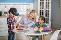 Curly boy and dark-haired girl sitting at round table with blonde female, boy wearing vr glasses, everybody smiling Royalty Free Stock Photo