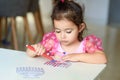 Curly brunette cute little toddler girl painting with color pen paper menorah and candle Jewish holiday Chanukah.