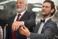 Curly brunette salesman helping costomer choosing jacket. Royalty Free Stock Photo