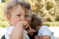 Curly child holds her hand to her mouth at the hands of men