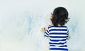 Curly cute little baby girl drawing with crayon color on the wall. Works of child Royalty Free Stock Photo