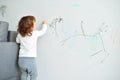 Curly cute little baby girl drawing with crayon color on the wall. Works of child Royalty Free Stock Photo