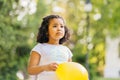 Curly cute sad hispanic dark skinned girl kid play with yellow balloon outdoor in summer. Summer, childhood, leisure