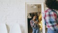 Curly funny african american girl dancing and singing with hair dryer in front of mirror at home